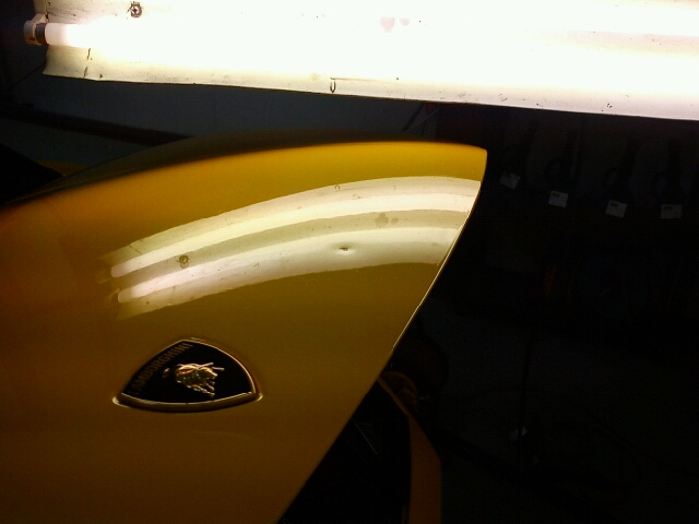 Close-up of a Lamborghini panel showing a flawless, reflection-perfect finish after paintless dent removal